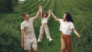 Joyful family moment in a green field during summer, capturing love and playfulness.
